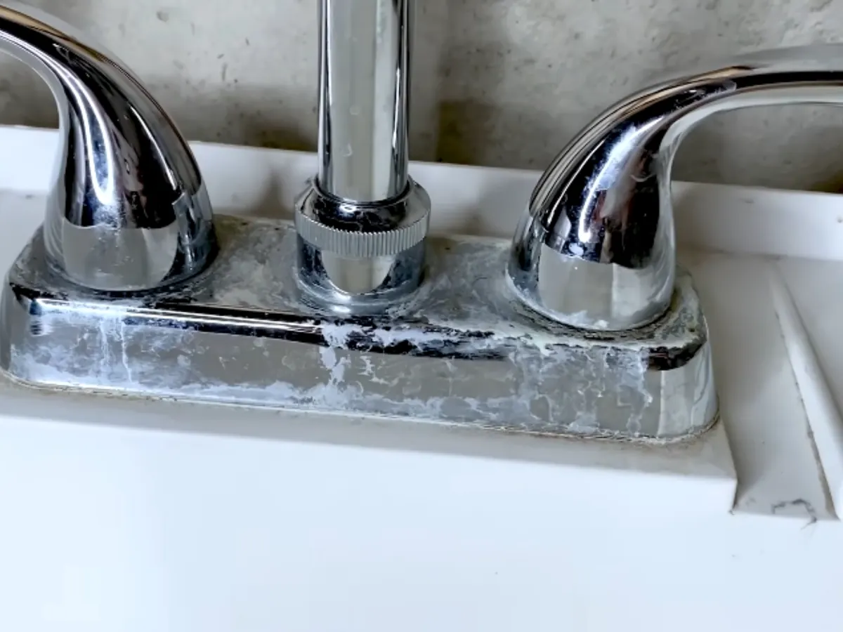 White mineral scale built up around a bathroom faucet from hard water